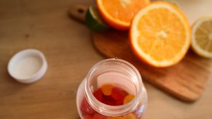 a jar filled with gummy bears next to sliced oranges