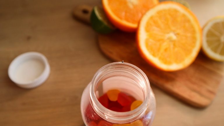 a jar filled with gummy bears next to sliced oranges
