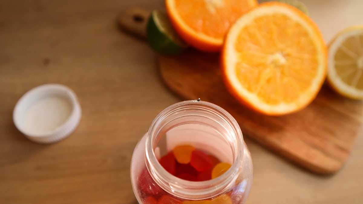 a jar filled with gummy bears next to sliced oranges
