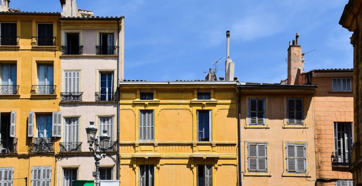 Historic pastel-colored buildings under blue sky in Aix-en-Provence, France.