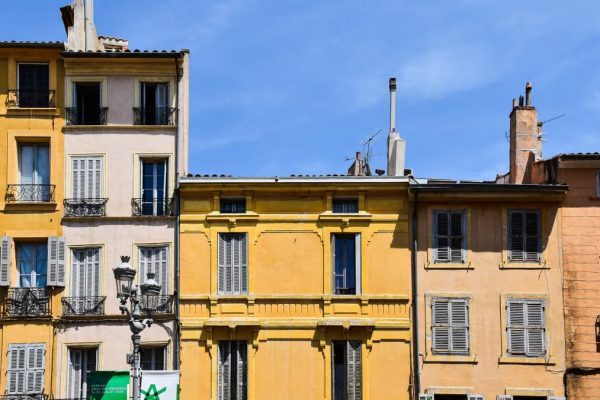Historic pastel-colored buildings under blue sky in Aix-en-Provence, France.